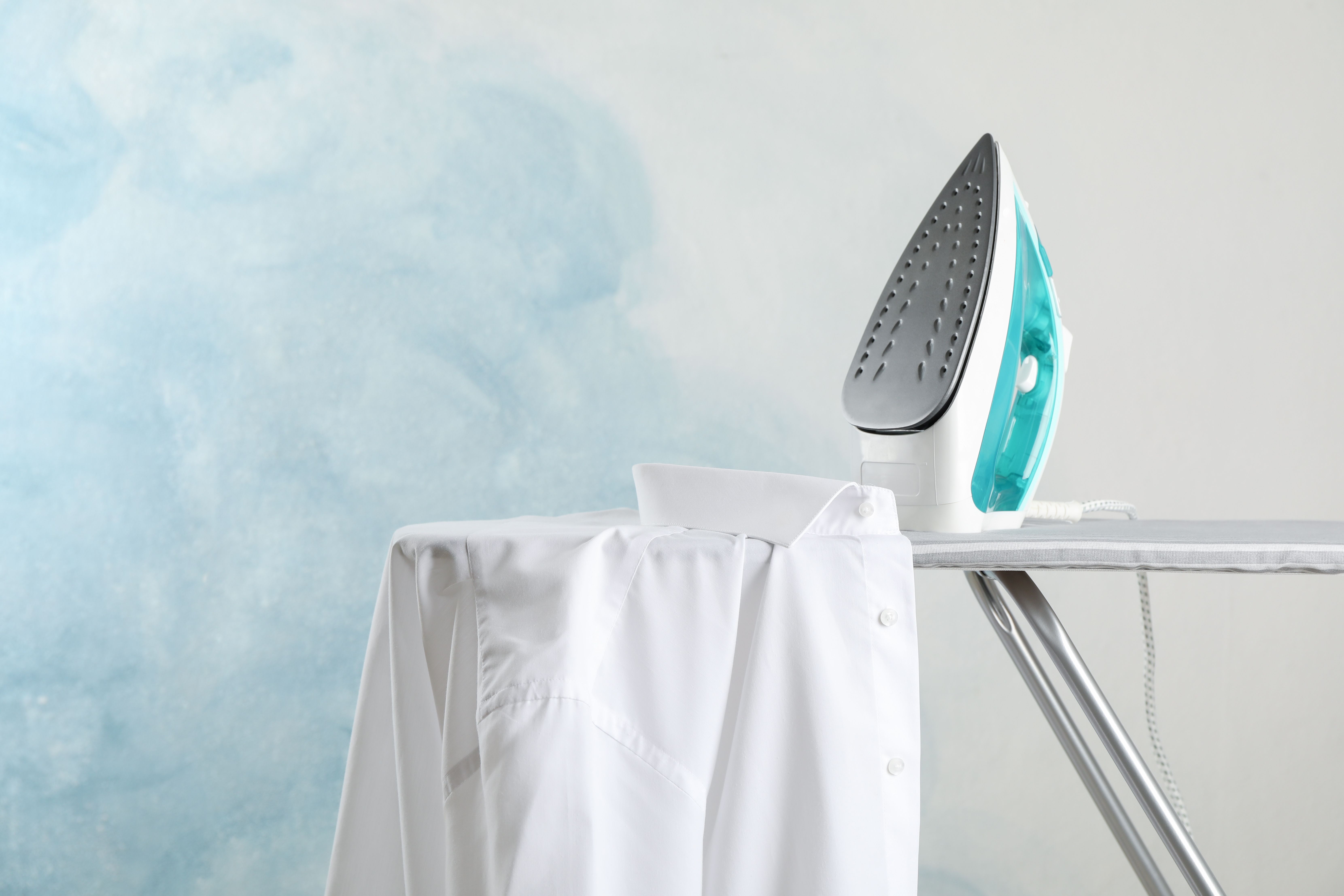 Electric iron on ironing board with white shirt – ideal for fixing transfer prints and fabric paints on T-shirts.