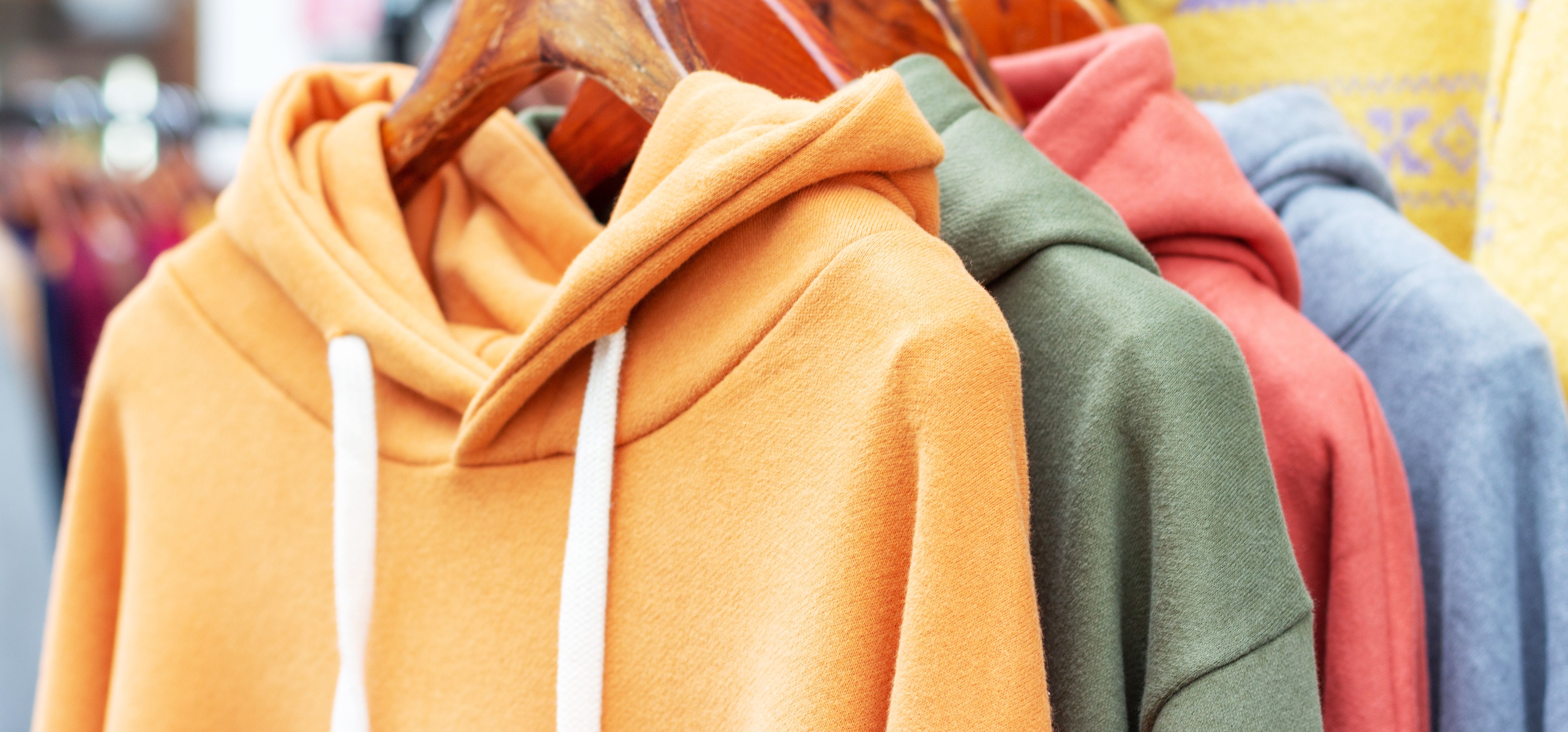 Colorful sweatshirts on hangers – detailed view of vibrant hoodies, sweaters, and jumpers.