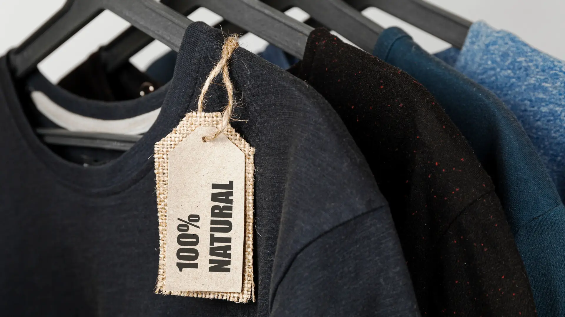 Kleidung aus 100% natürlichen Materialien – Bio T-Shirts auf Kleiderbügeln mit Nachhaltigkeitsetikett