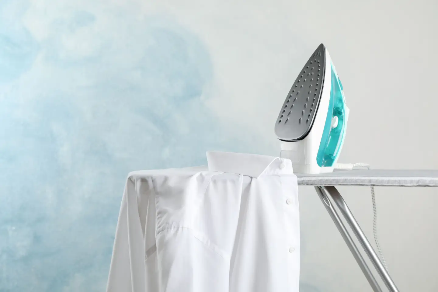 Elektrobügeleisen auf Bügelbrett mit weißem Hemd – ideal zur Fixierung von Transferdruck und Textilfarben auf T-Shirts.